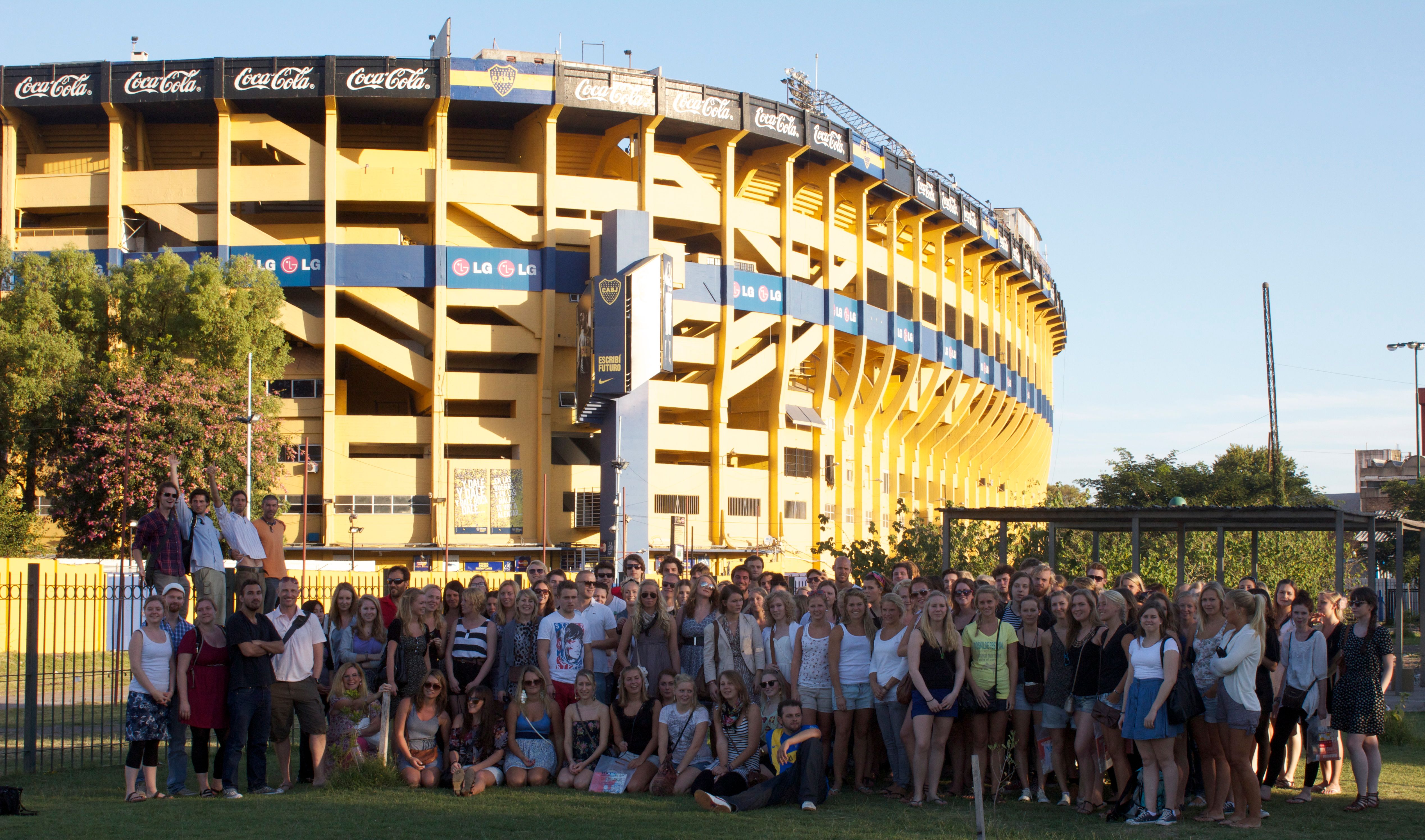 en stor grupp människor poserar för en bild framför en arena.