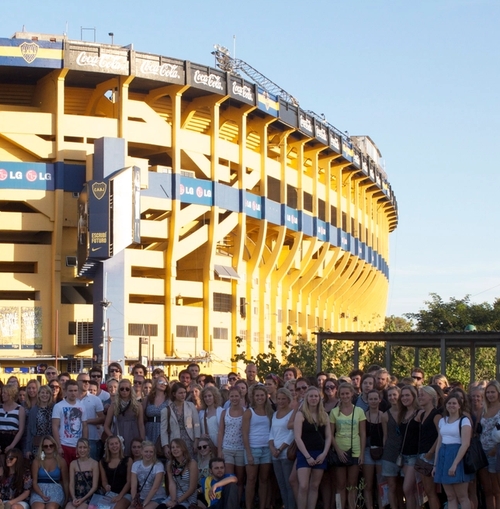 a large group of people are posing for a picture in front of a stadium.