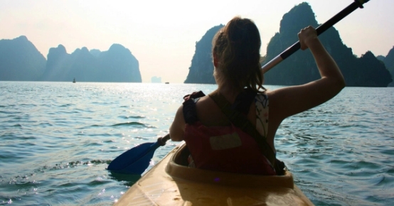 a woman is paddling a kayak in the ocean .