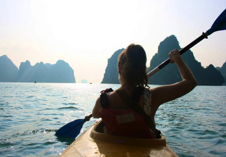 a woman is paddling a kayak in the ocean .