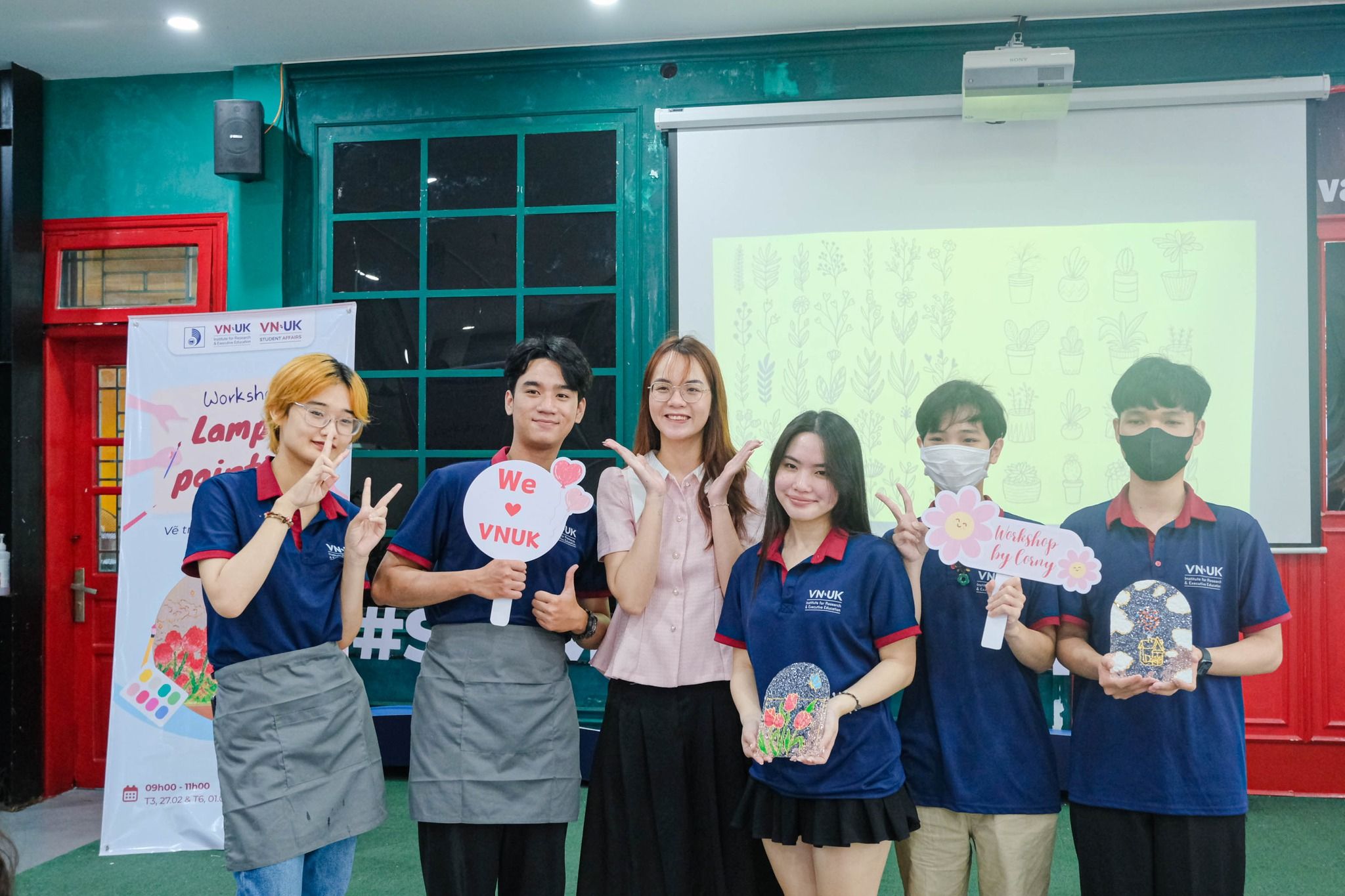 a group of people are posing for a picture in front of a projector screen .