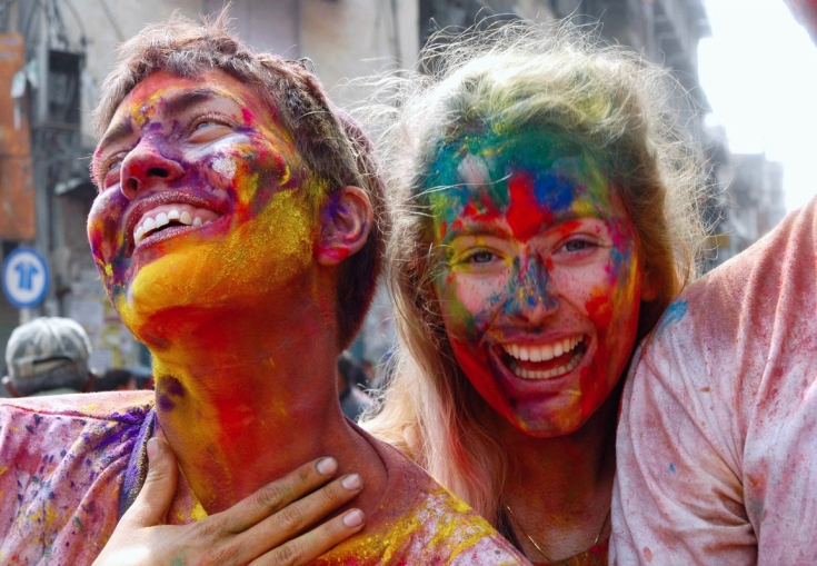a man and a woman are covered in colored powder and smiling