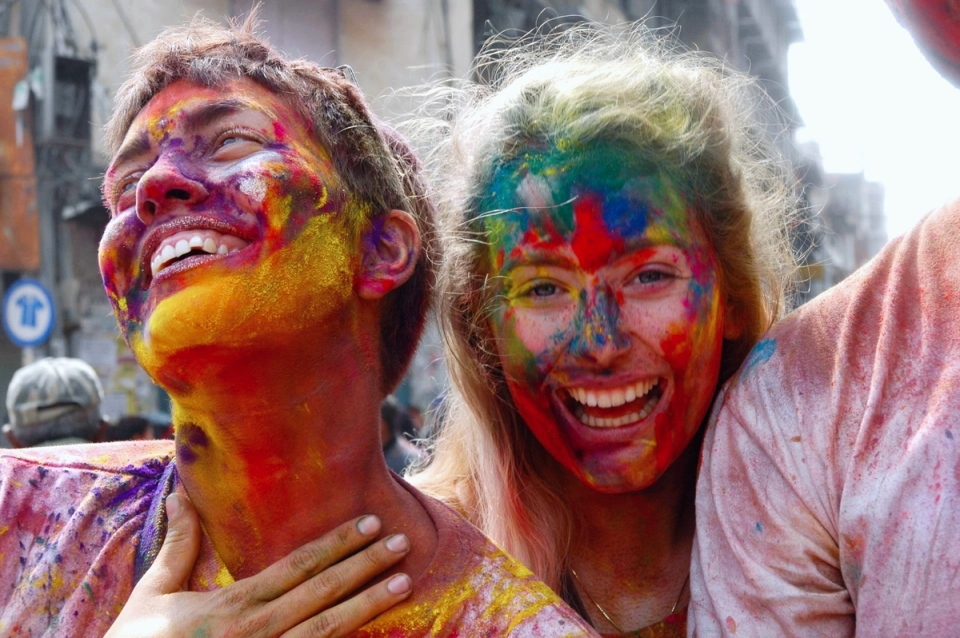 a man and a woman are covered in colored powder and smiling