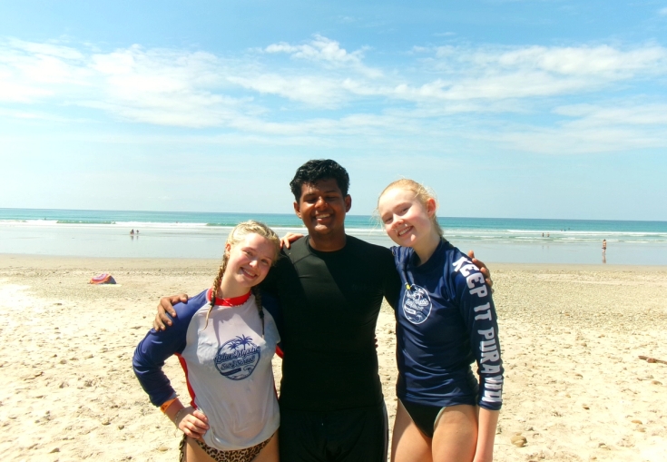 a man and two girls are posing for a picture on the beach .