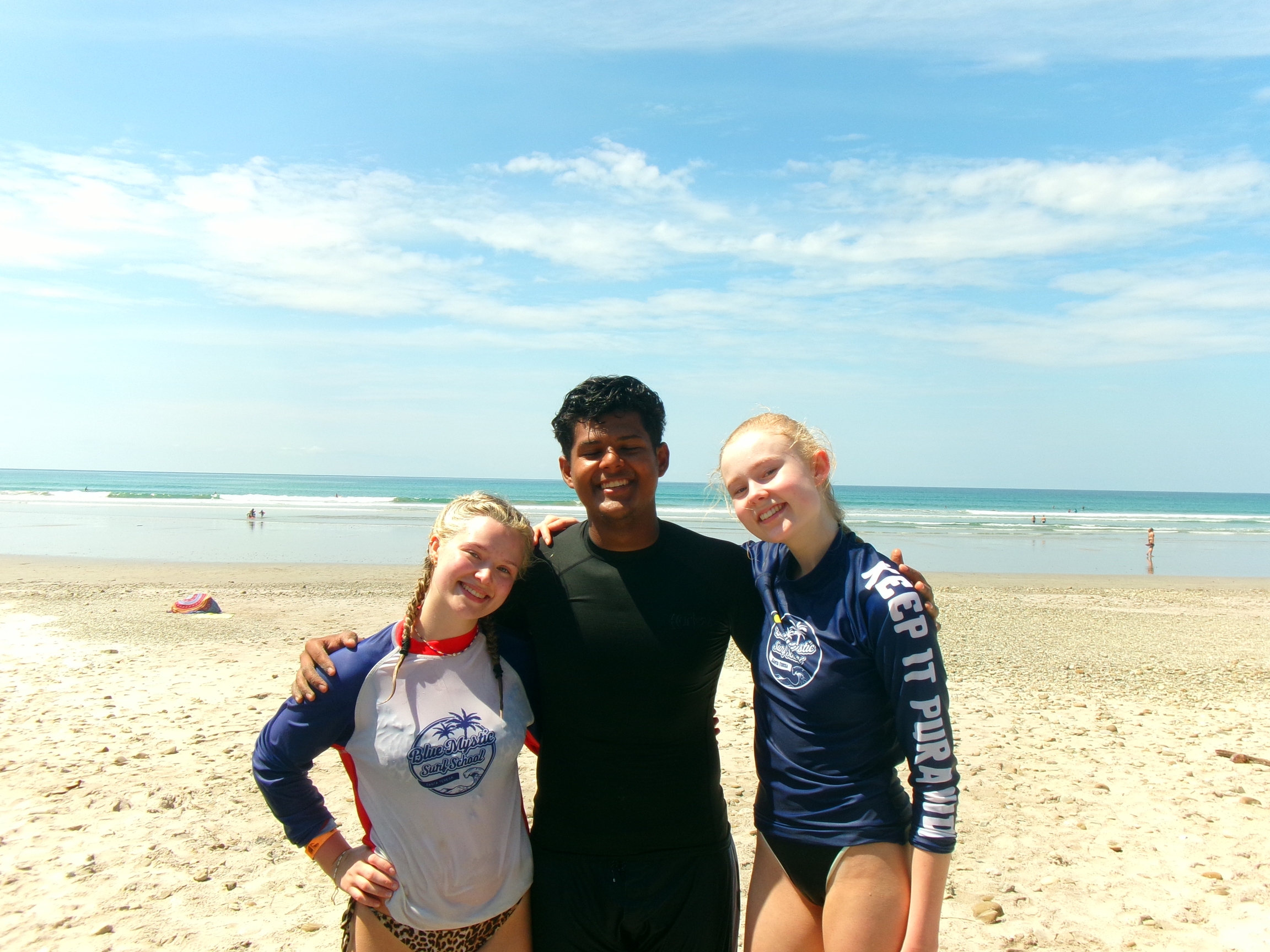 a man and two girls are posing for a picture on the beach .