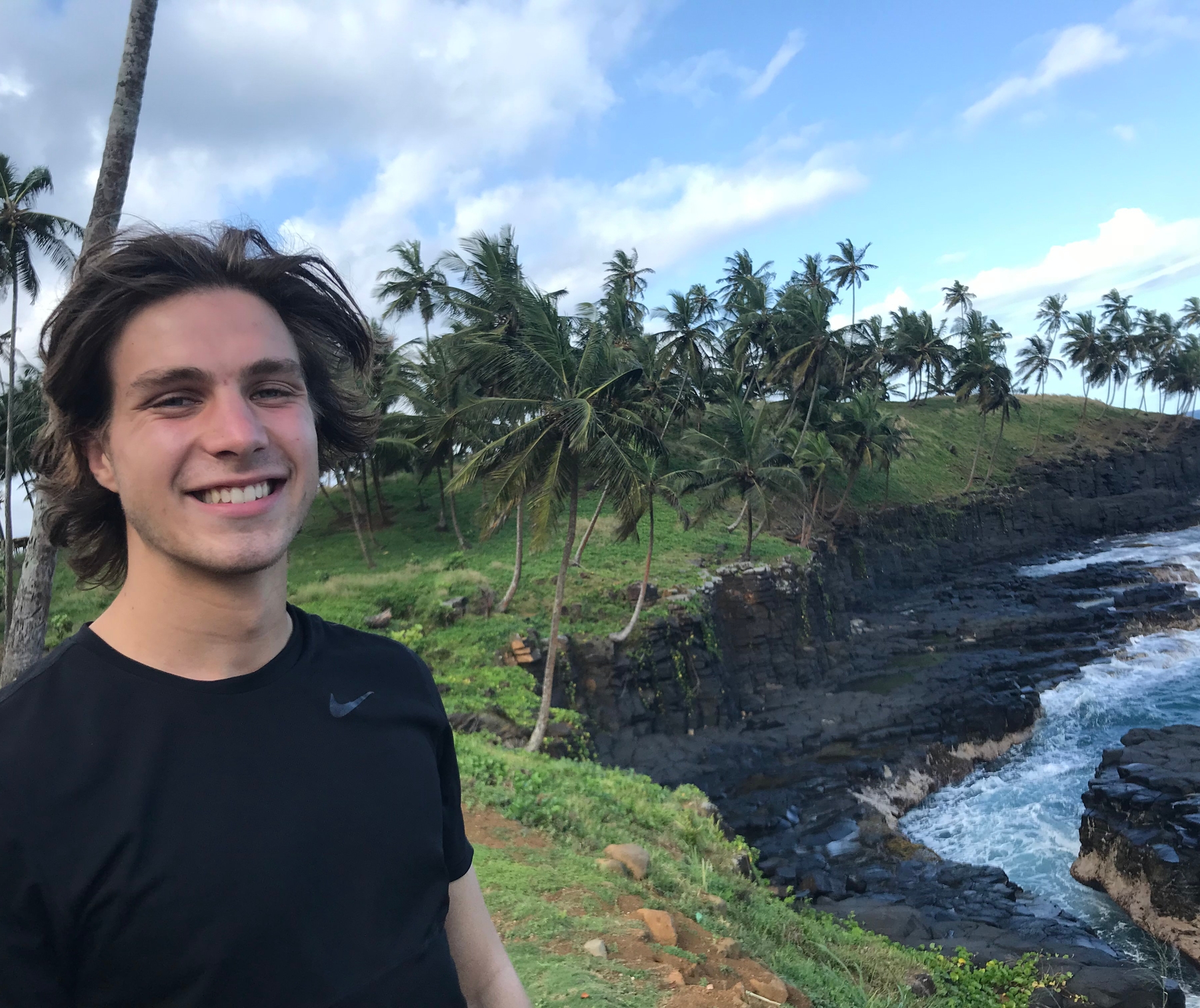 a young man is standing on a cliff overlooking the ocean.