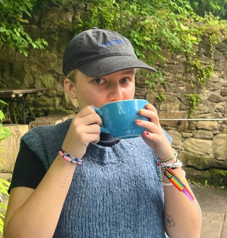 a woman wearing a hat is drinking from a blue cup .