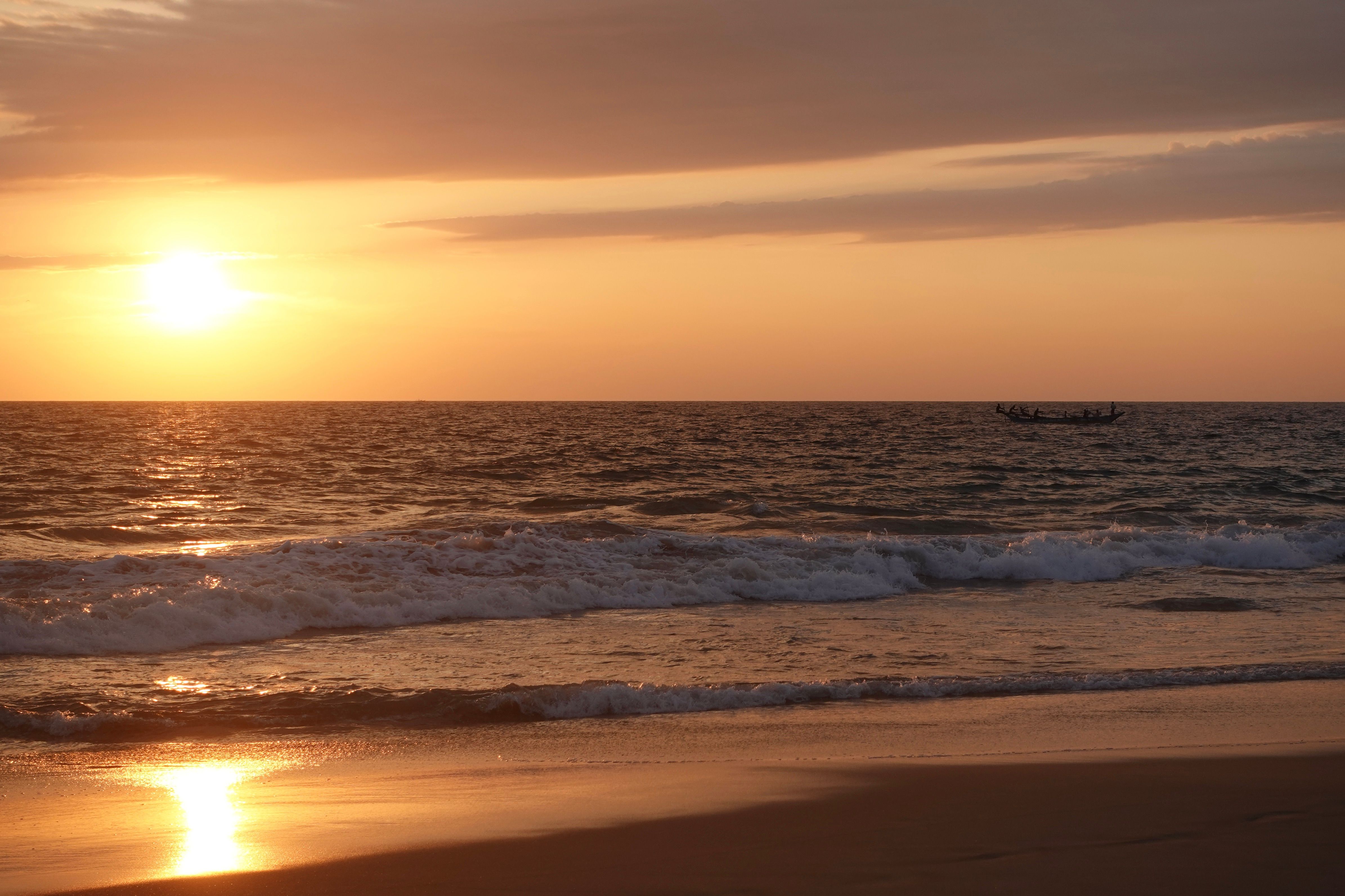 the sun is setting over the ocean with a boat in the distance