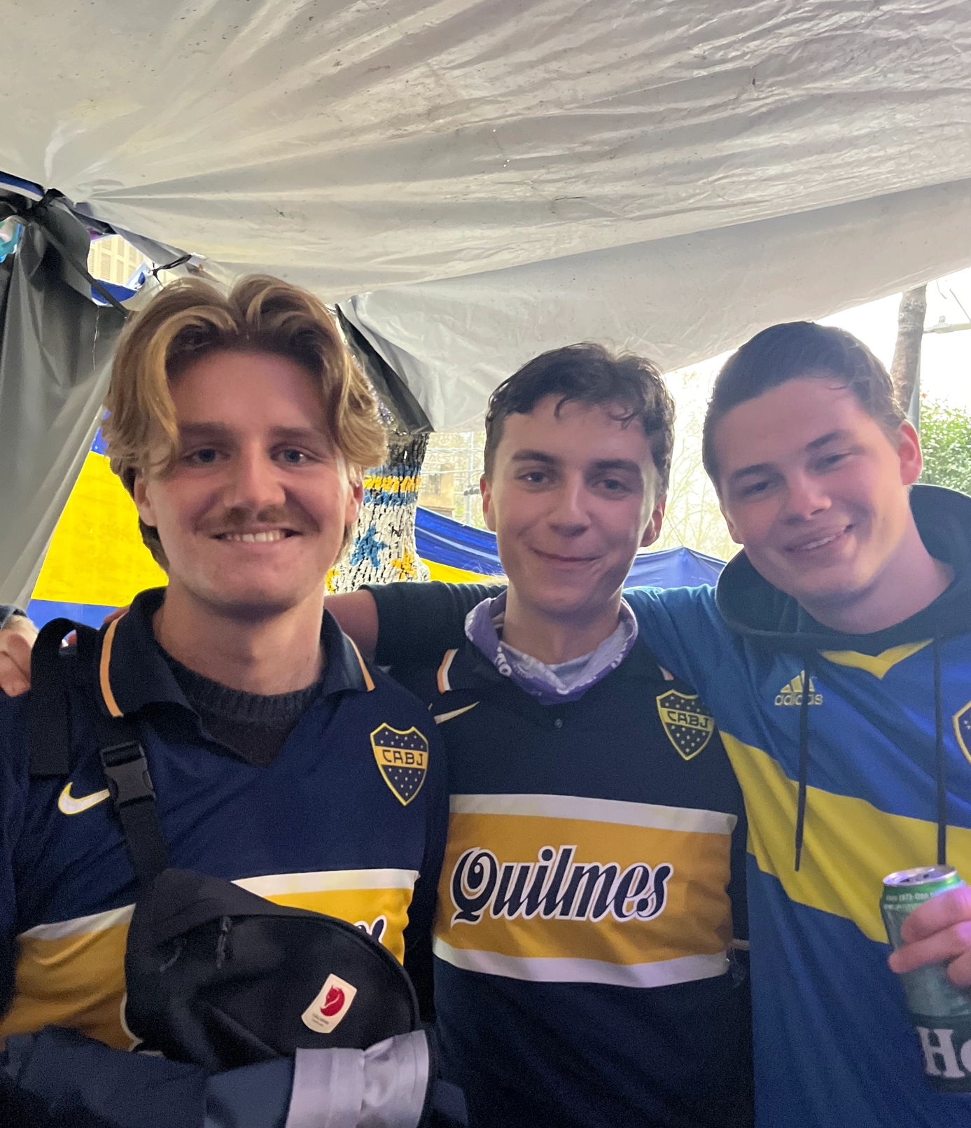 three young men are posing for a picture with one wearing a quilmes jersey