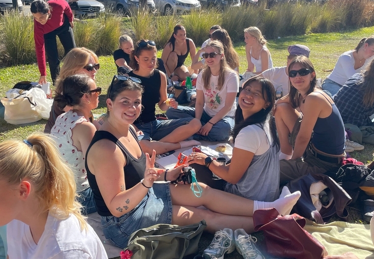 a group of people are sitting on the grass in a park .