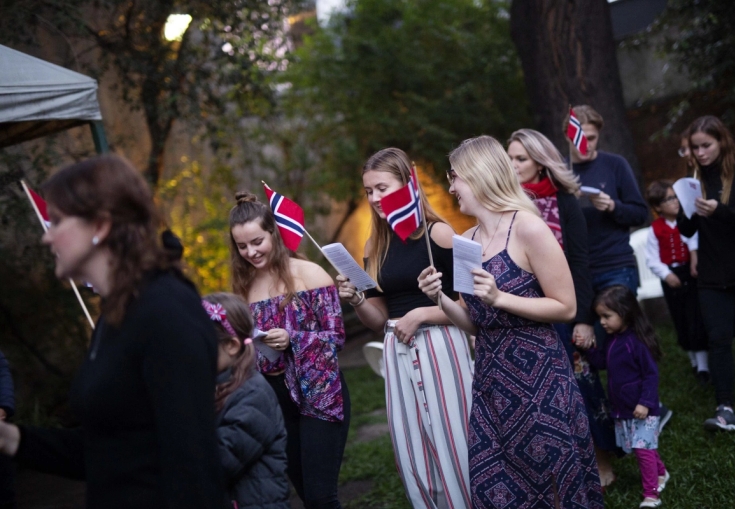 en gruppe mennesker står i en linje holder flagg og synger.