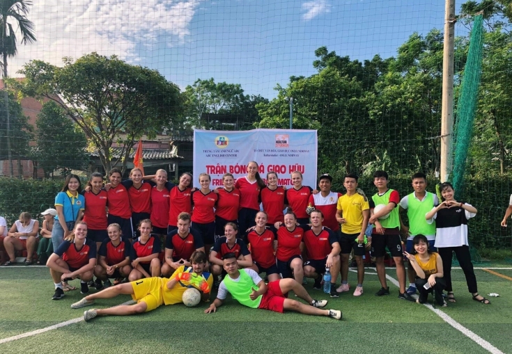 a group of people are posing for a picture on a soccer field .
