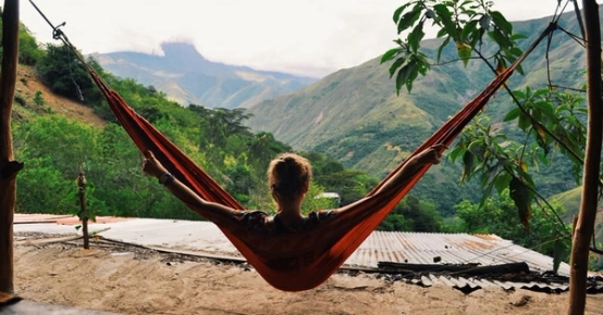 en kvinna ligger i en hängmatta med bergen i bakgrunden