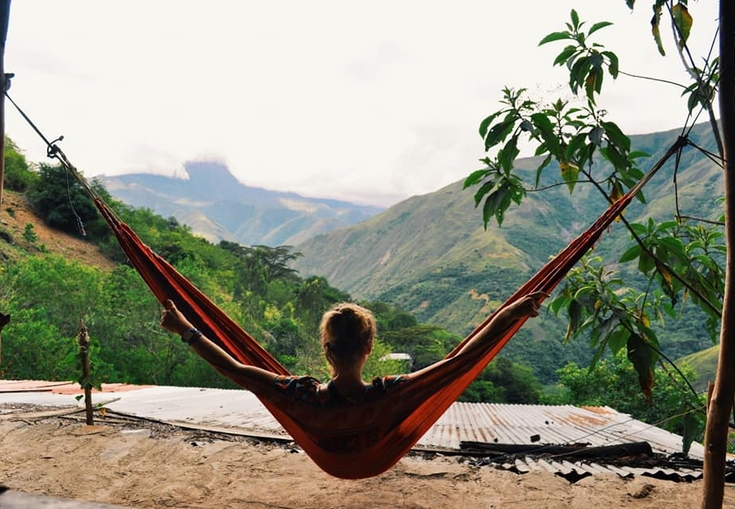en kvinna ligger i en hängmatta med bergen i bakgrunden