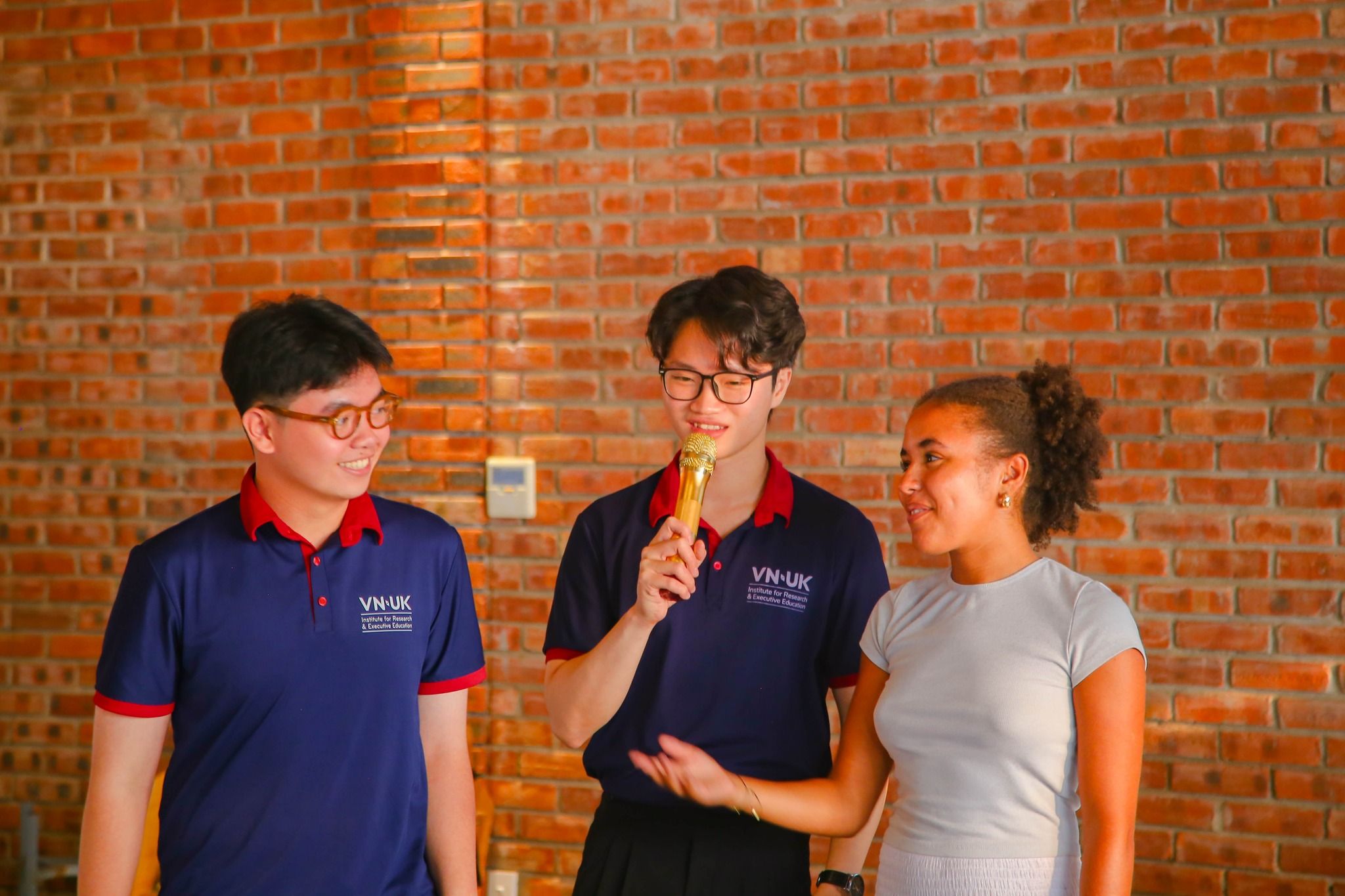 a group of young people are standing next to each other in front of a brick wall .