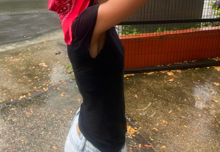 A person with a red bandana covering their head, standing in the rain.