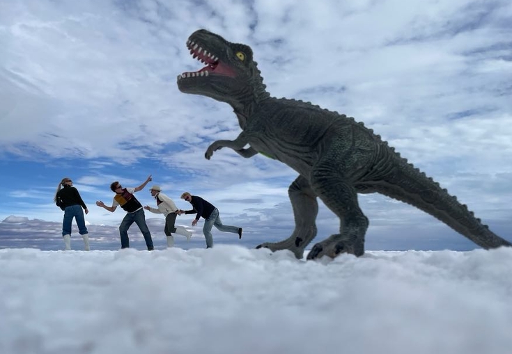 a group of people are standing in front of a toy dinosaur .