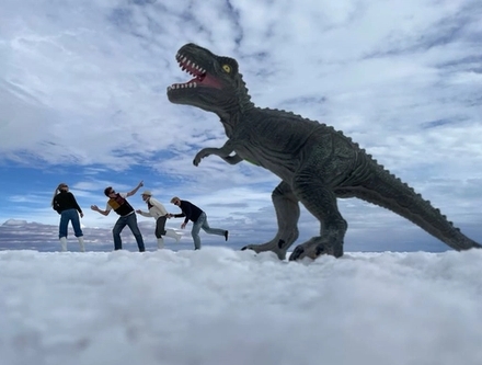 a group of people are standing in front of a toy dinosaur .