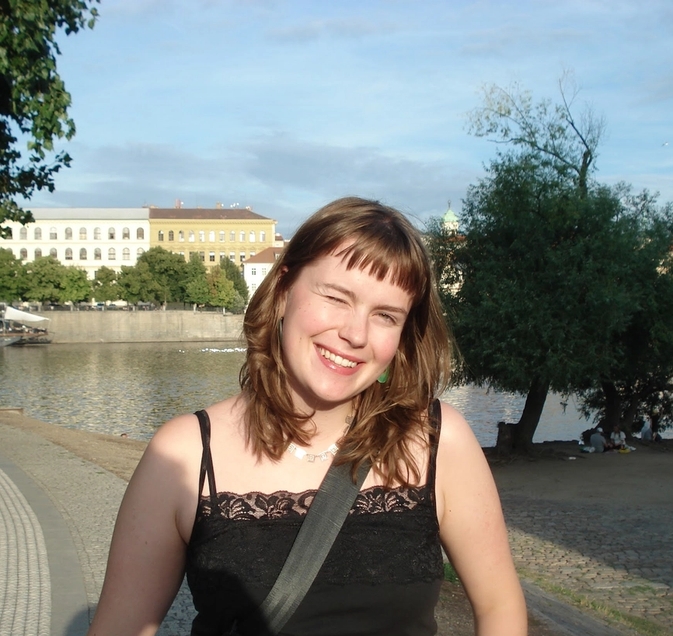 a woman in a black tank top is smiling in front of a body of water .