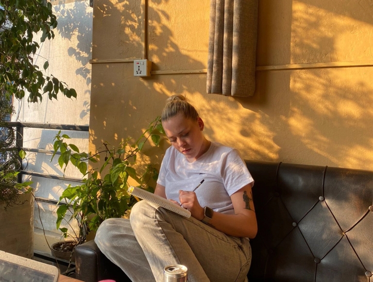 en kvinne sitter på en sofa og skriver i en notatbok.