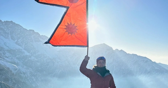 en person står på toppen av et fjell med et oransje flagg