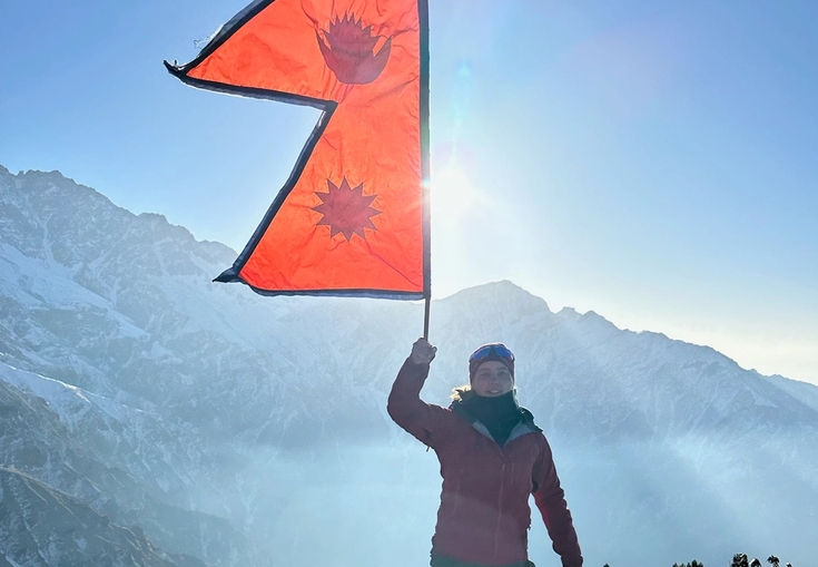 a person standing on top of a mountain with an orange flag