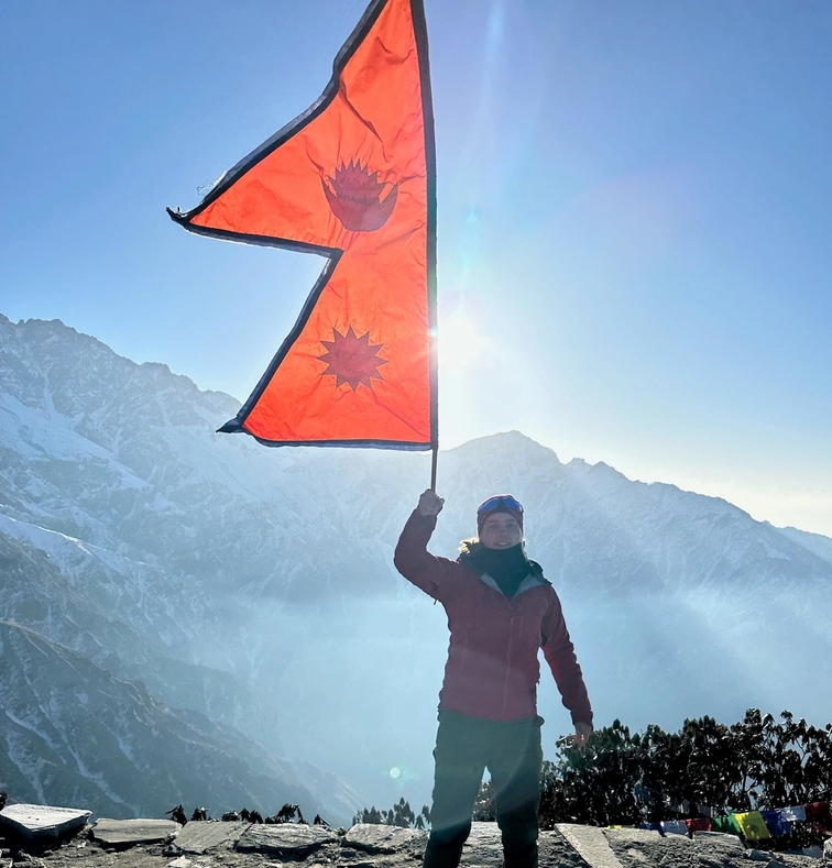 en person står på toppen av ett berg med en orange flagga