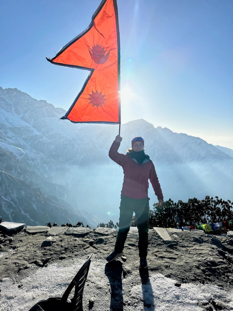 en person står på toppen af et bjerg med et orange flag