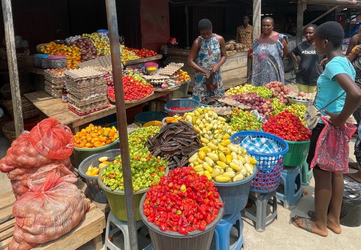 en grupp människor står runt en marknad och säljer frukt och grönsaker.