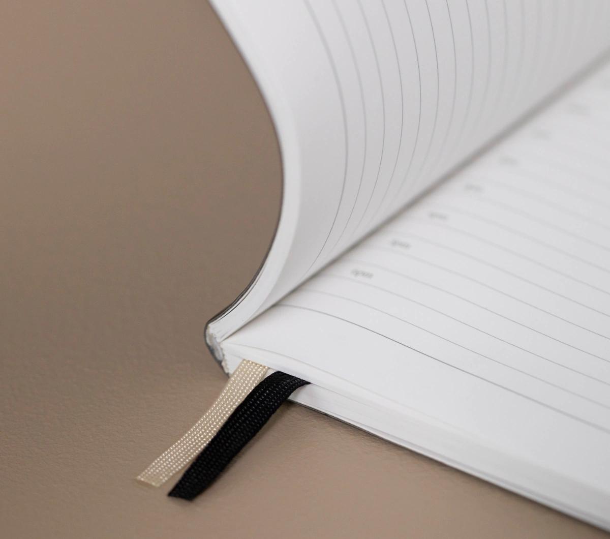 Double ribbon bookmarks and an expandable back pocket for the details that keep your day moving forward.