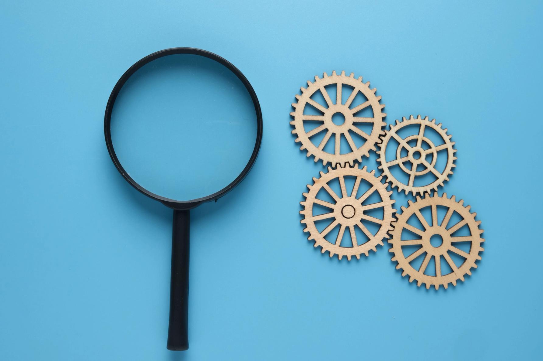 a magnifying glass next to some cogs