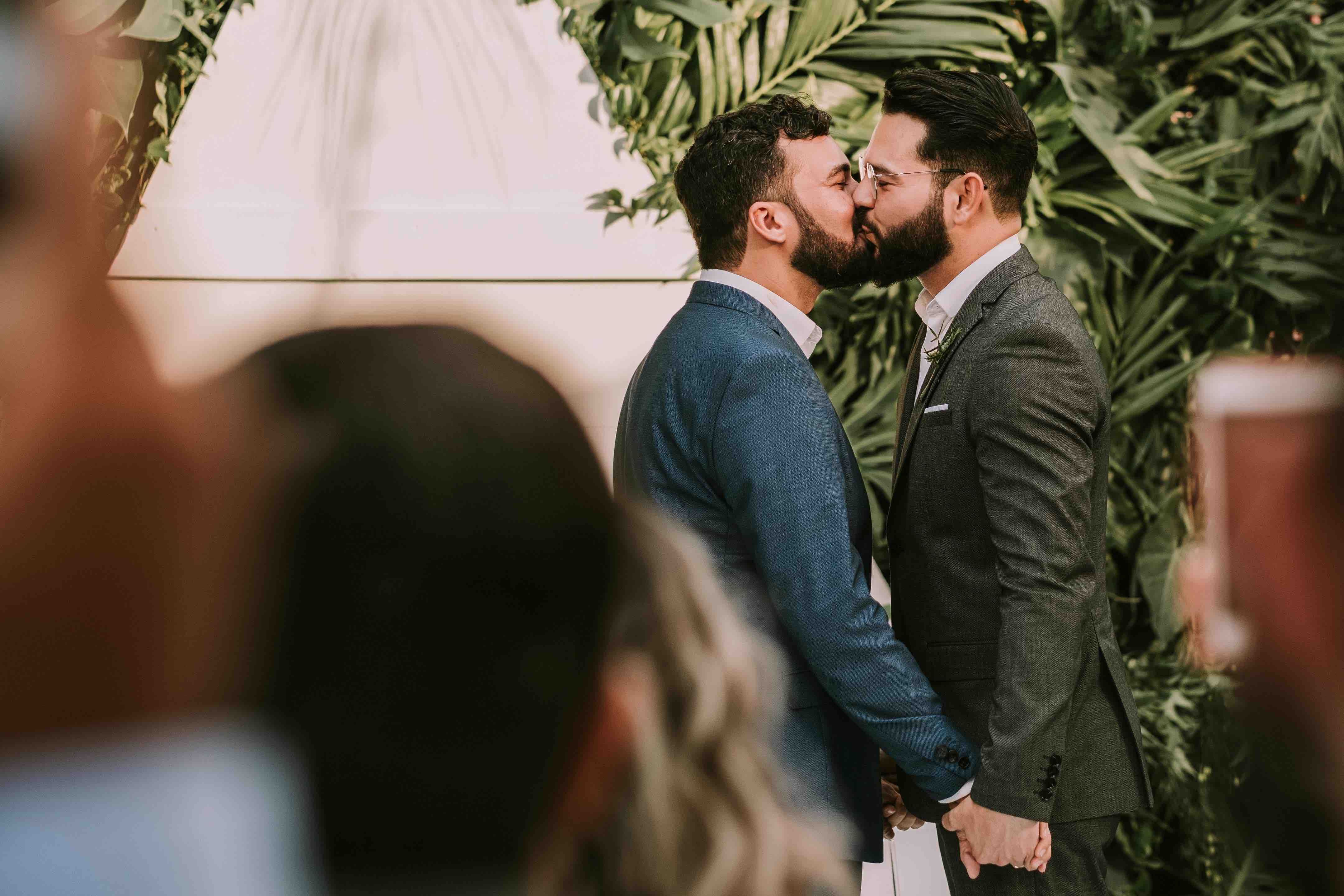two bearded grooms kissing at their wedding
