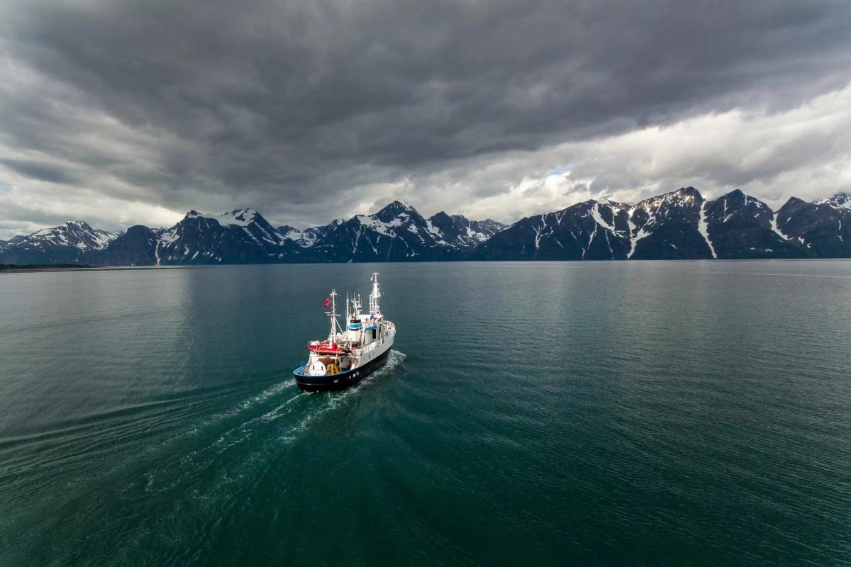 A ship crossing a fjord in front of mountains