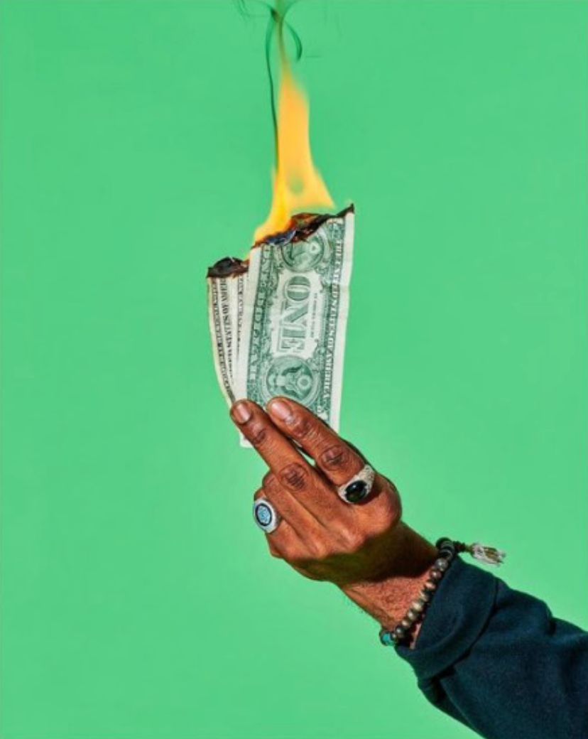 photo of hand holding burning dollar bills against green background