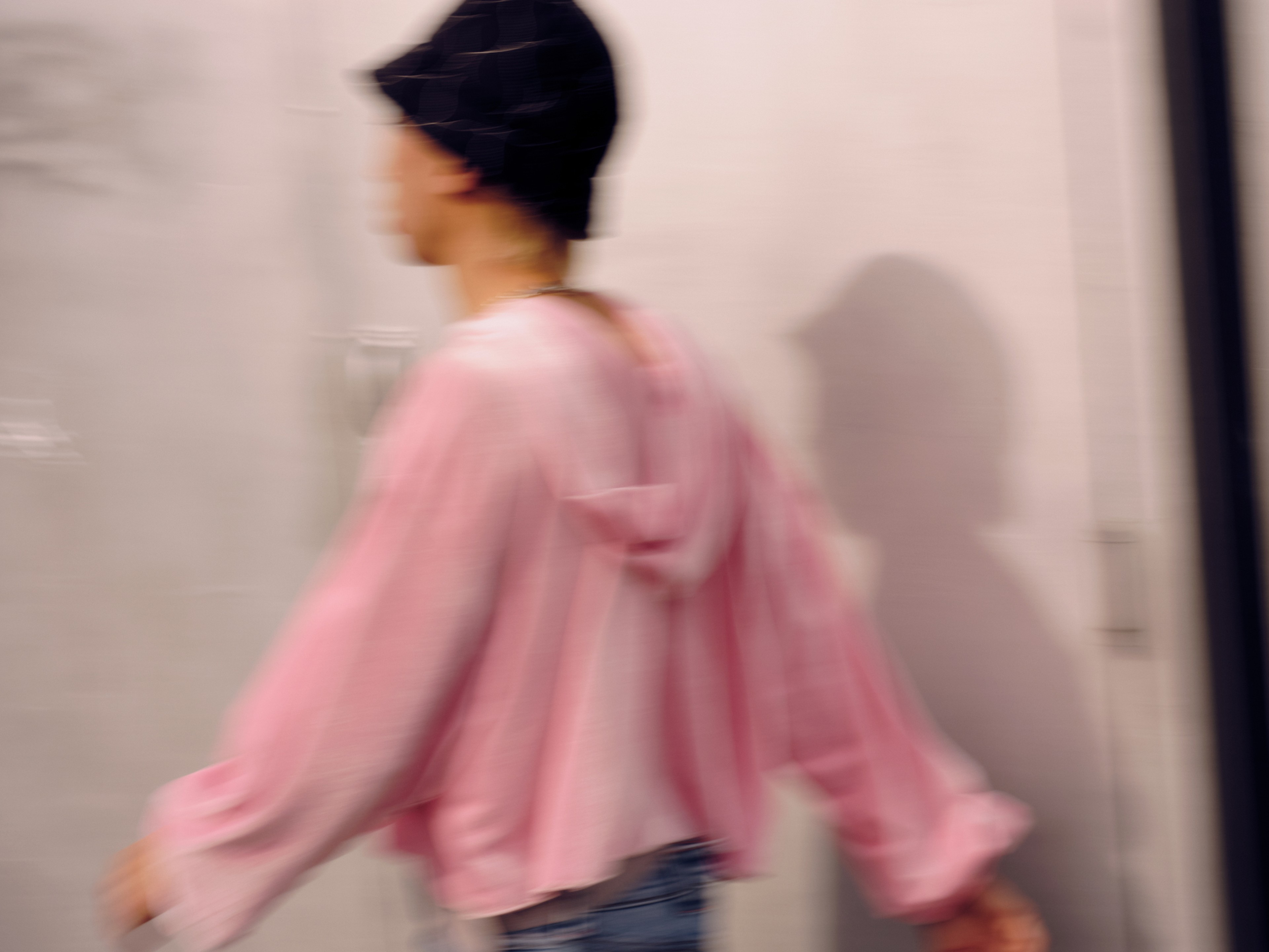 blurry photo of a man wearing a bucket cap and a pink jacket walking