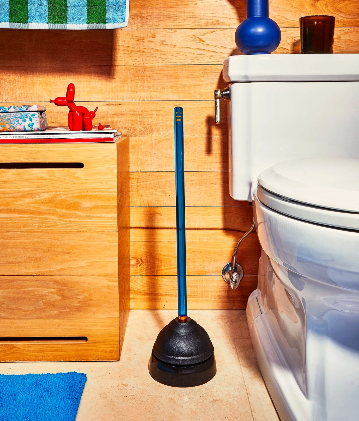single blue staff plunger in situ next to toilet and cabinet
