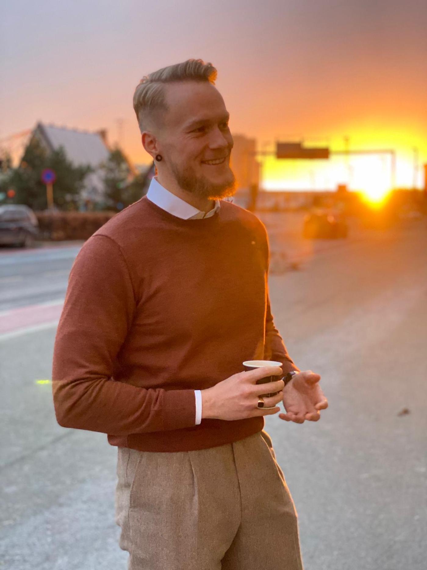 a man in a red sweater is holding a cup of coffee