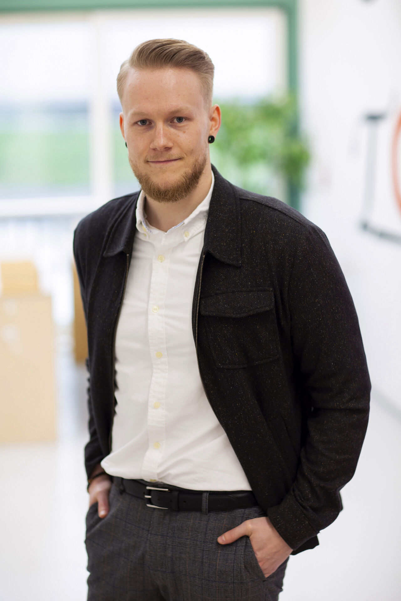 Kristoffer with a sharp haircut wearing a white shirt and a brown wool overshirt
