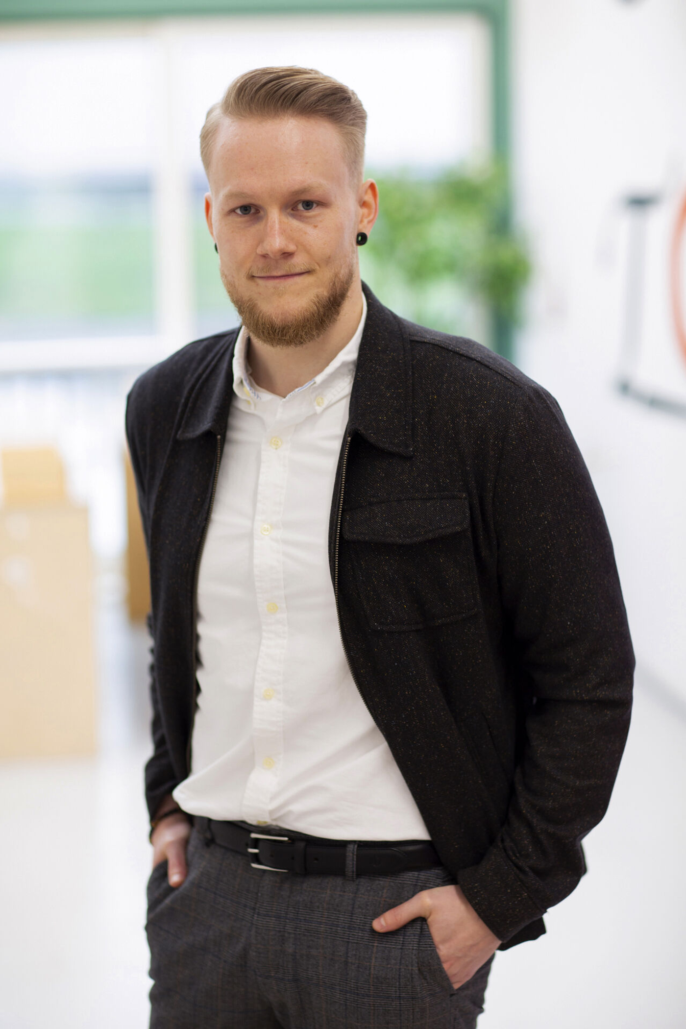 Kristoffer with a sharp haircut wearing a white shirt and a brown wool overshirt
