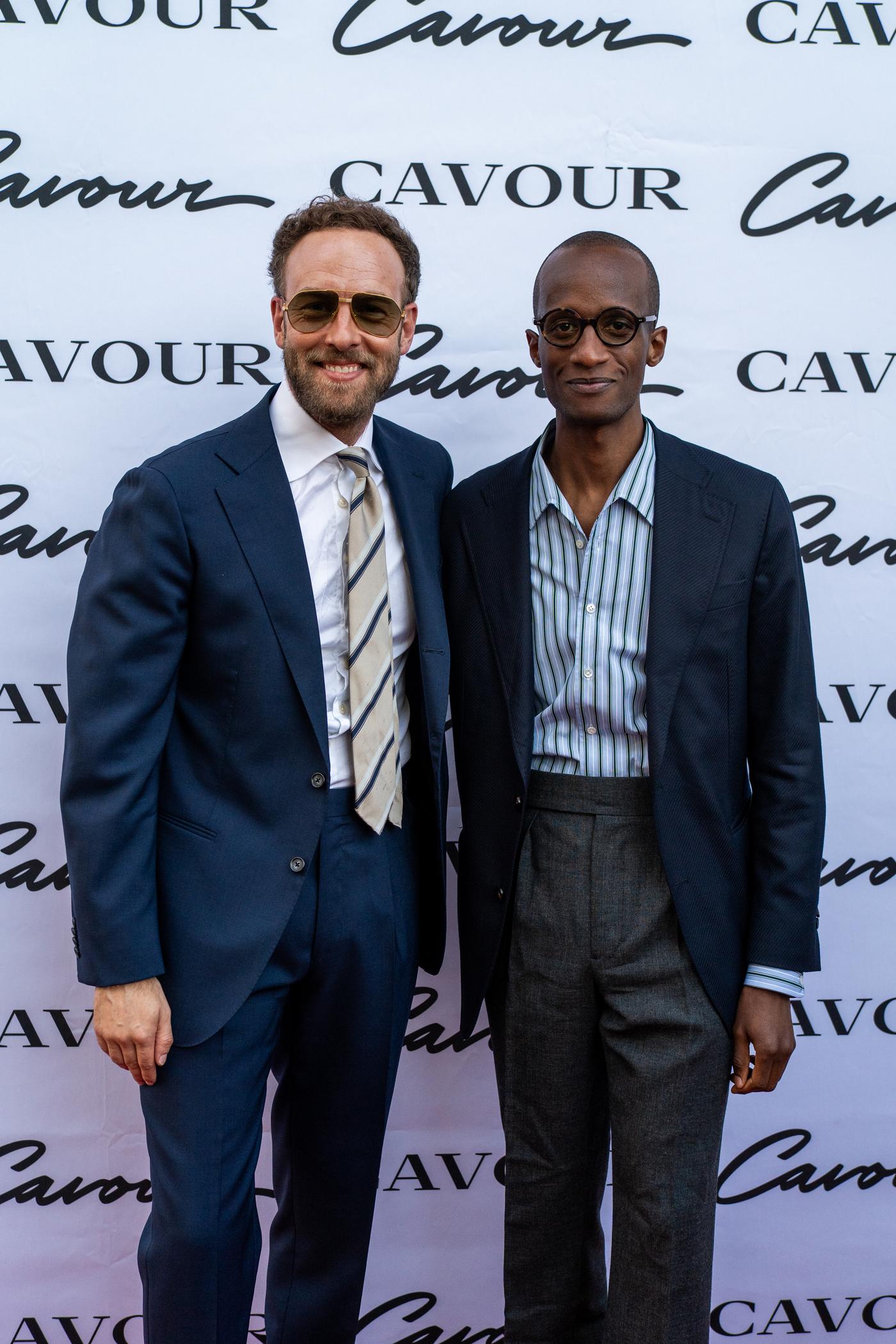 two men standing in front of a cavour sign
