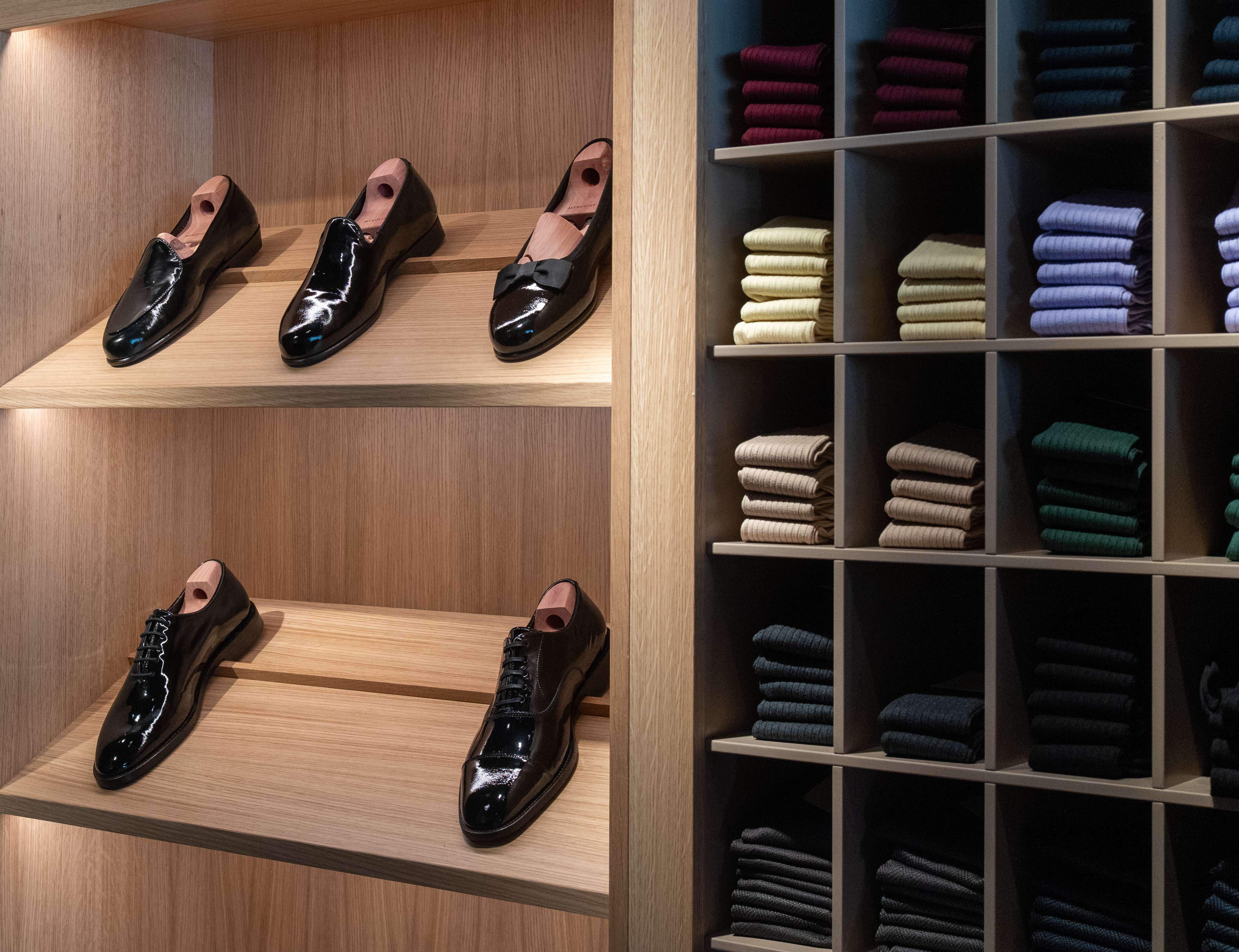 a pair of shoes sitting on top of a wooden shelf in a store .