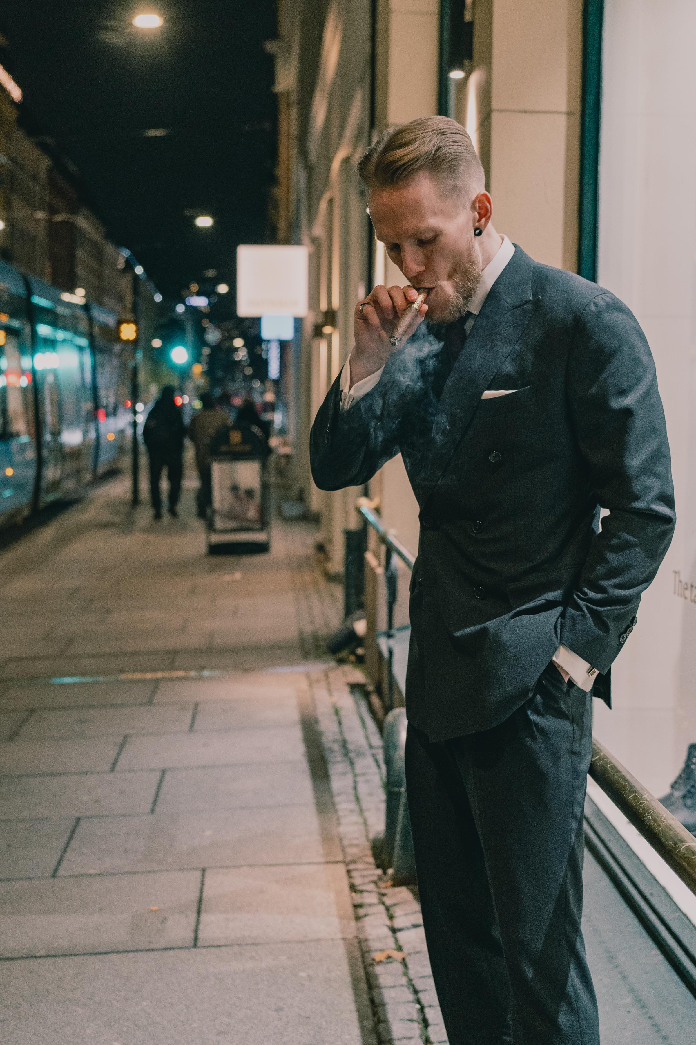 Kristoffer in a suit puffing a cigar