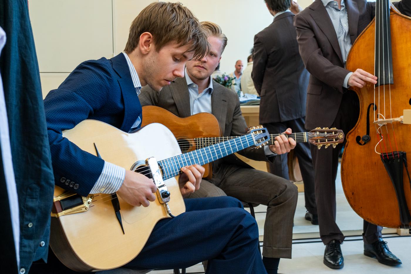 a man is playing a guitar while another man plays a double bass .