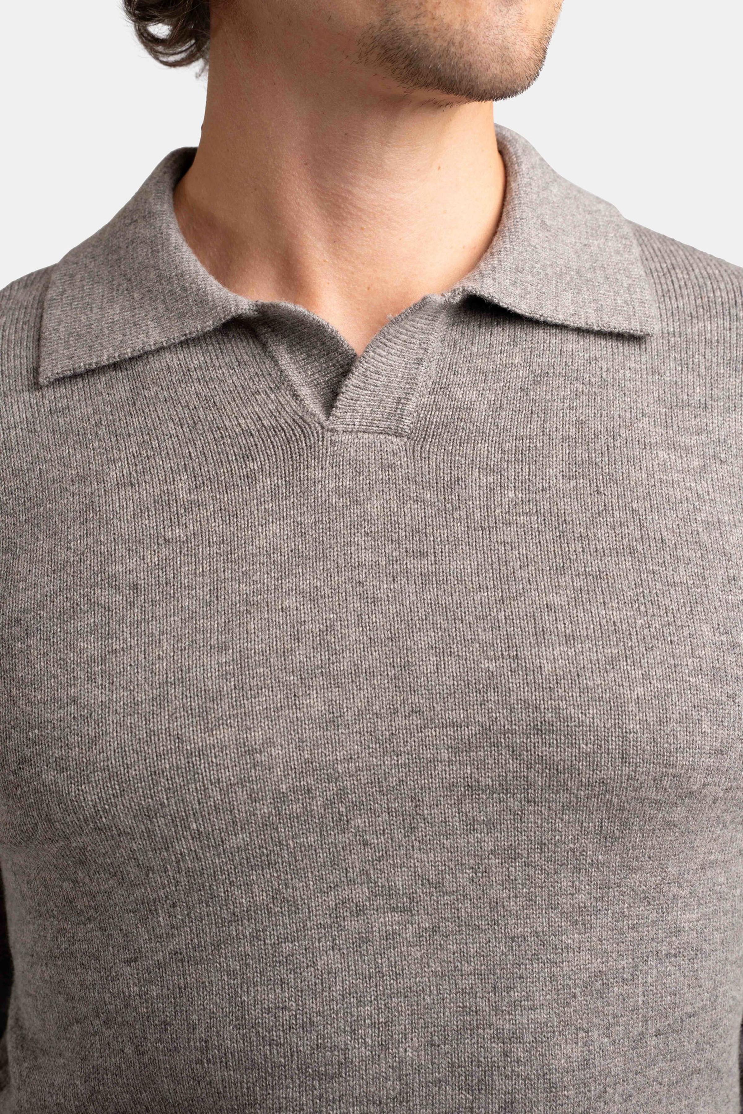 Close-up of a man wearing a grey knitted long-sleeve polo shirt.