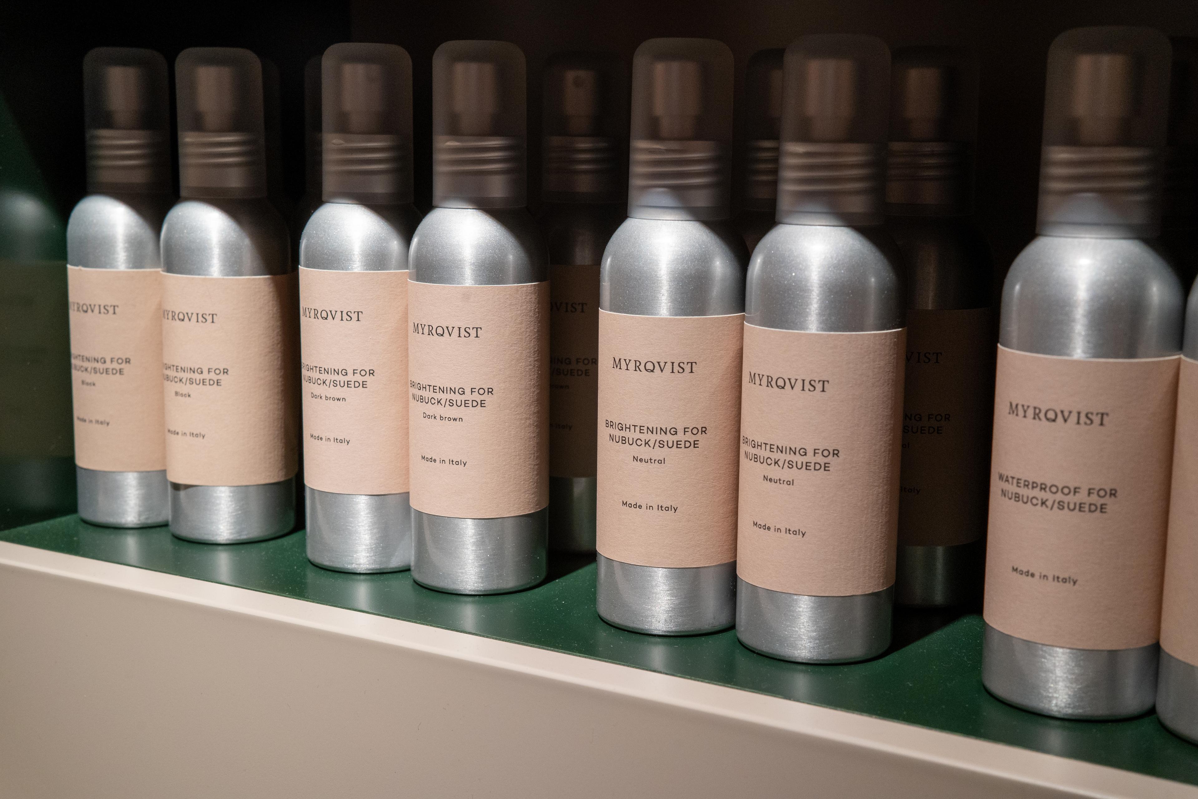 a row of spray bottles sitting on top of a shelf .