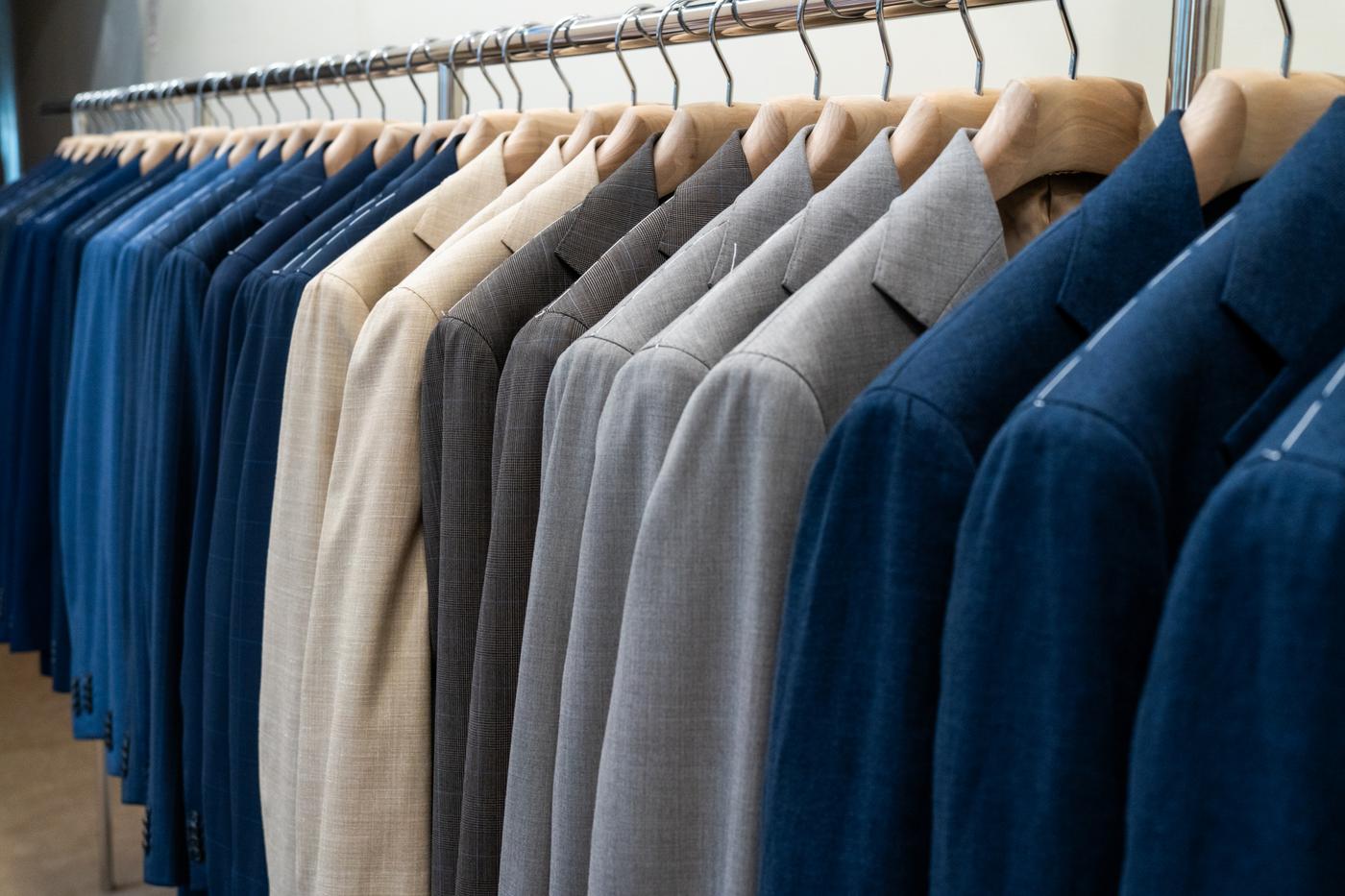 a row of suits hanging on a rack in a store .