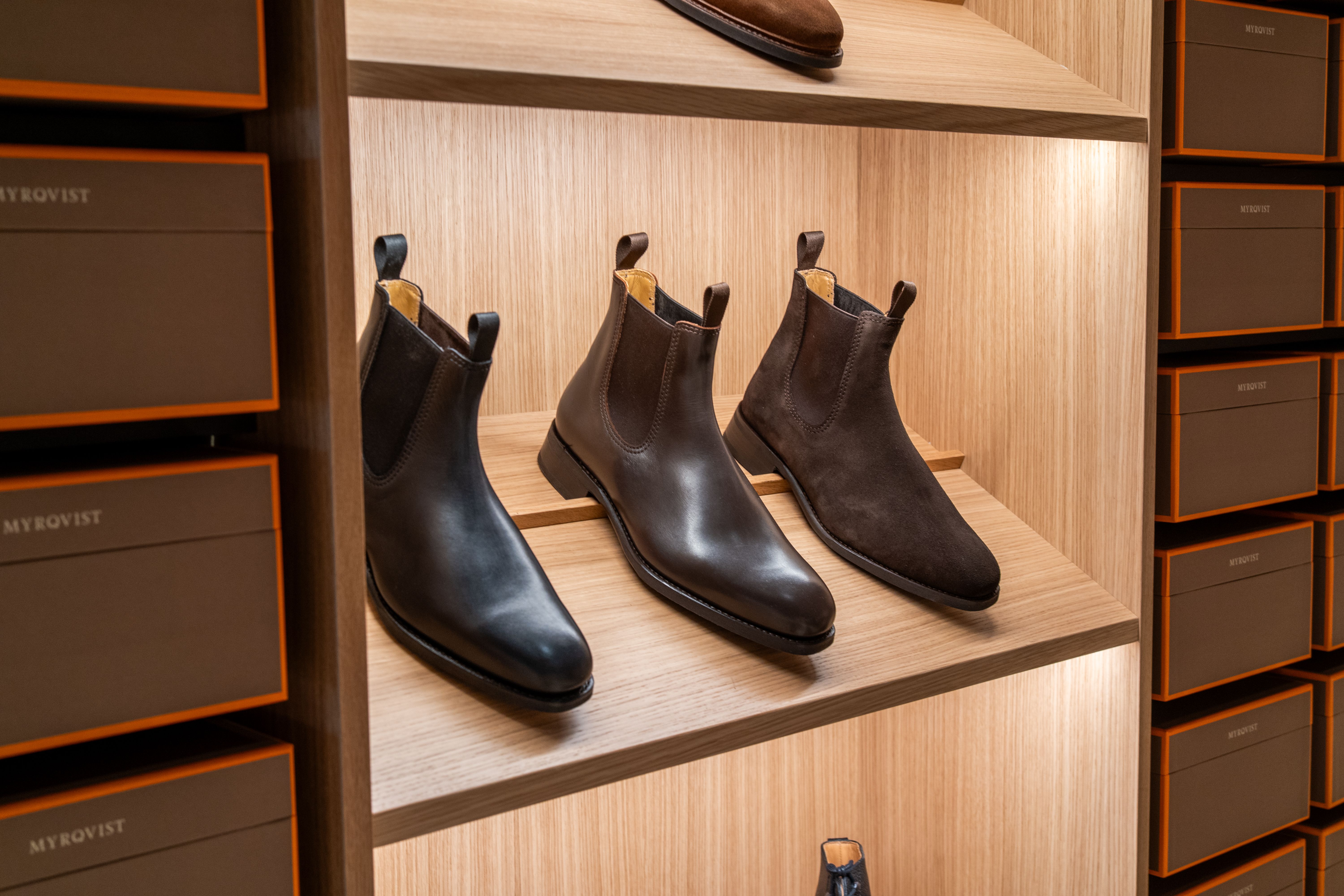 a pair of brown boots are sitting on a wooden shelf in a store .