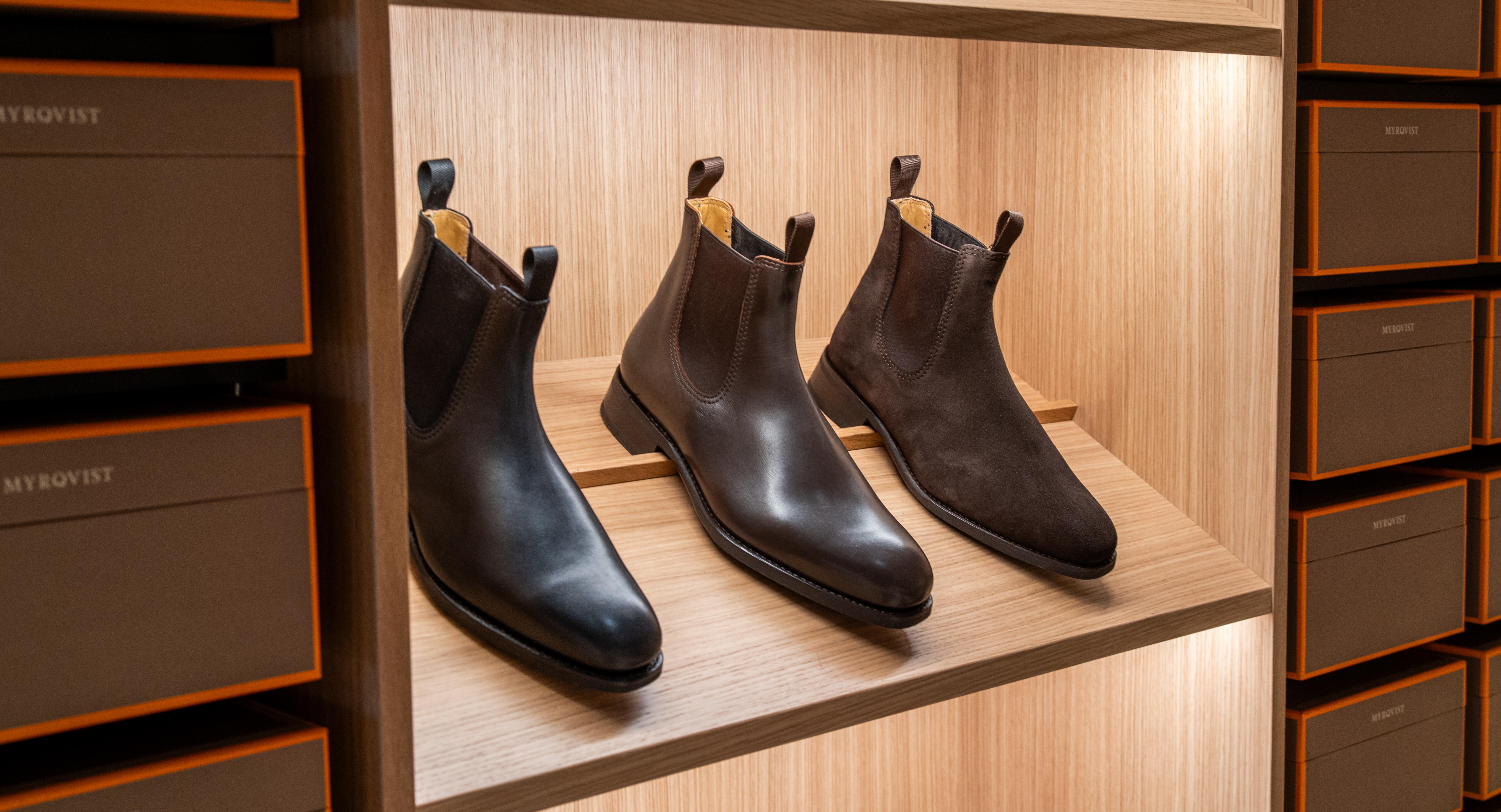 a pair of brown boots are sitting on a wooden shelf in a store .