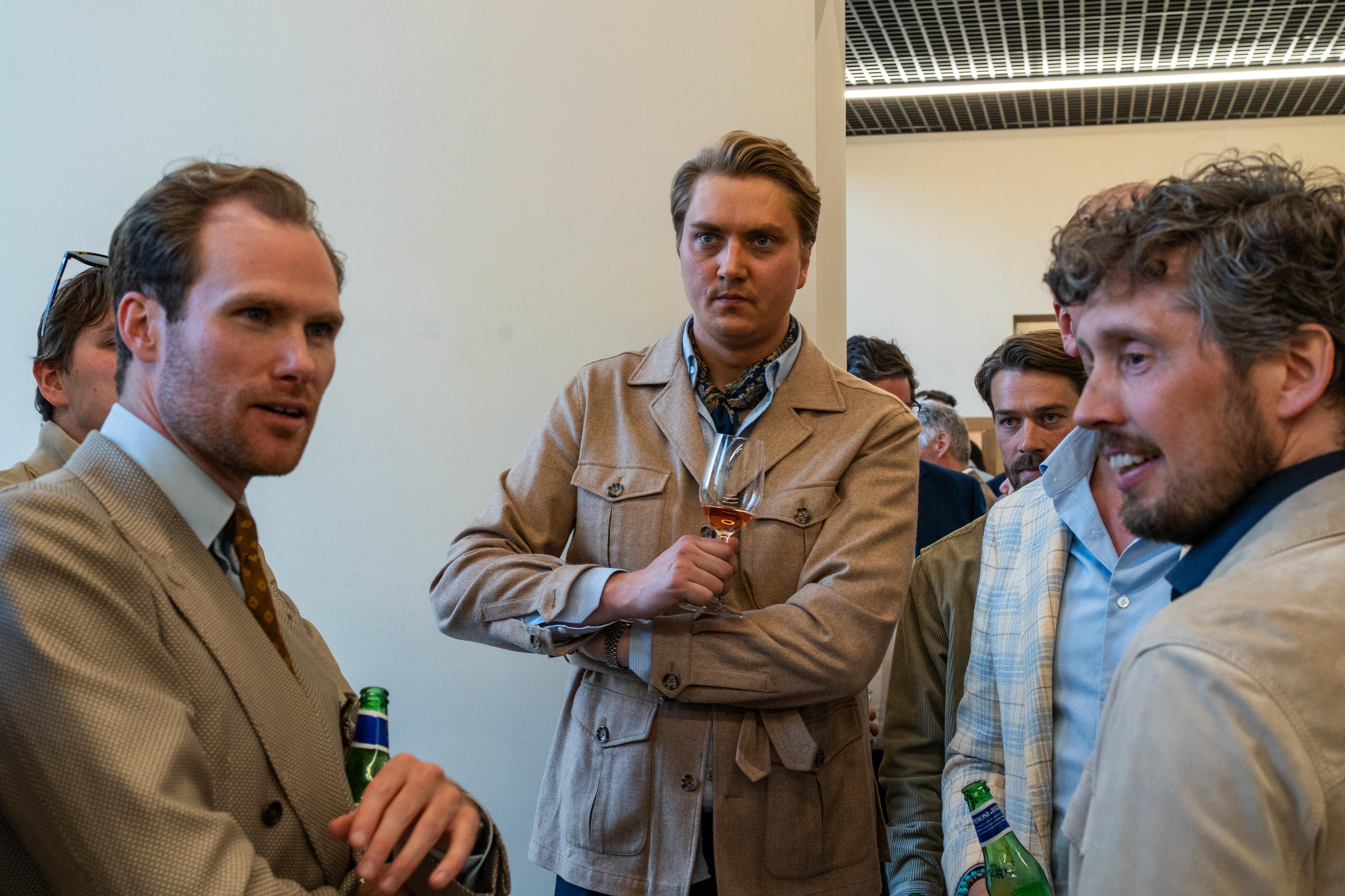 a group of men are standing in a room talking to each other .
