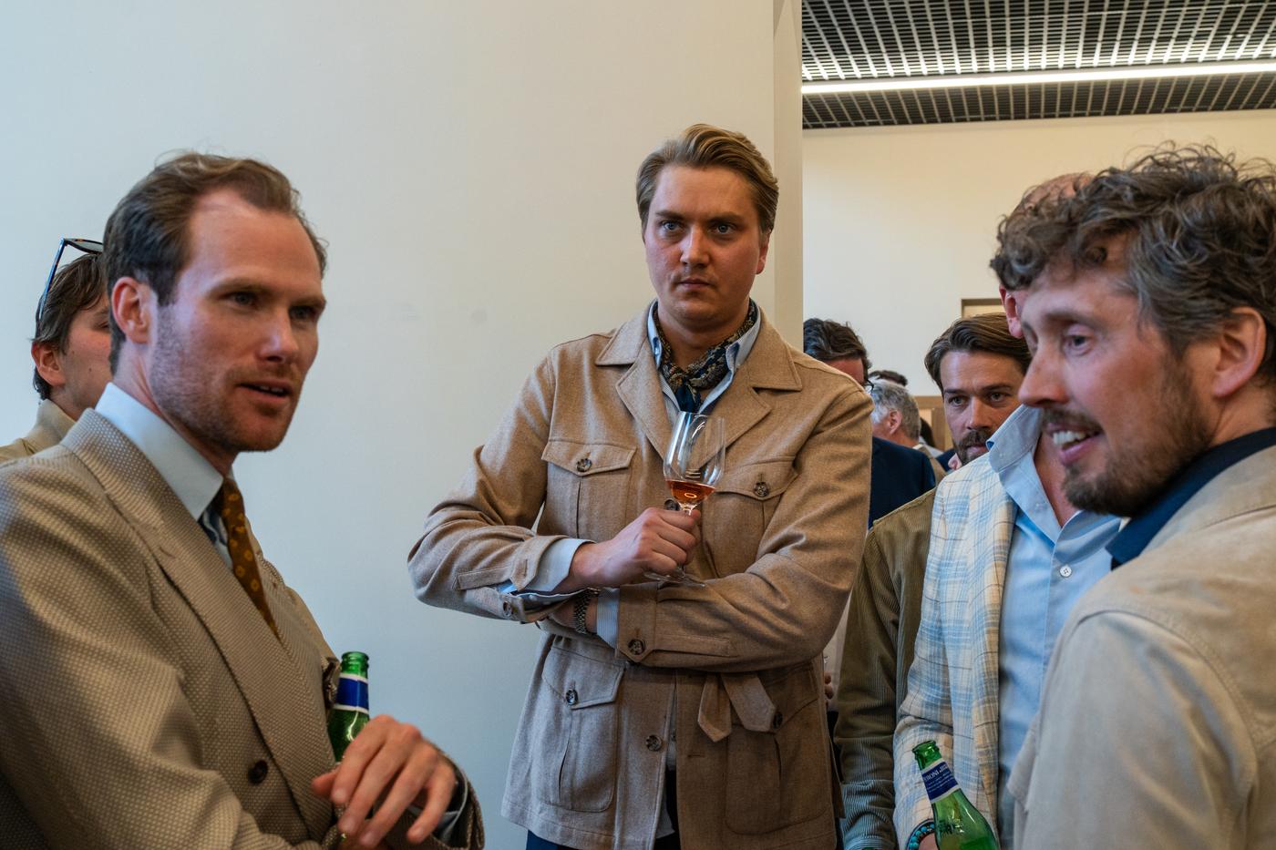 a group of men are standing in a room talking to each other .